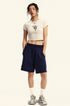 Model in a white cropped T-shirt with a graphic design, navy sweat shorts, white socks, and sneakers