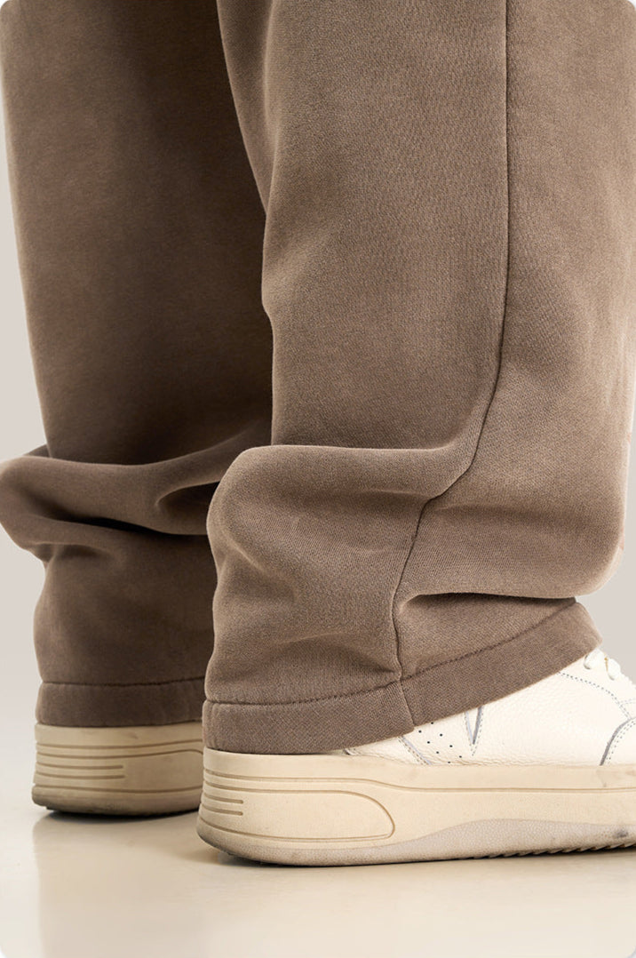 Close-up of taupe sweatpants leg and white sneaker showing casual hem styling