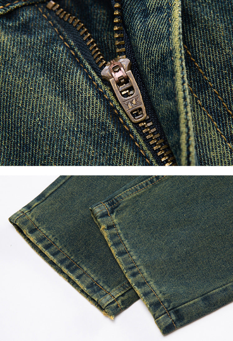 A close-up of the zipper and hem of faded greenish-blue denim jeans, highlighting the metal zipper and thick stitching