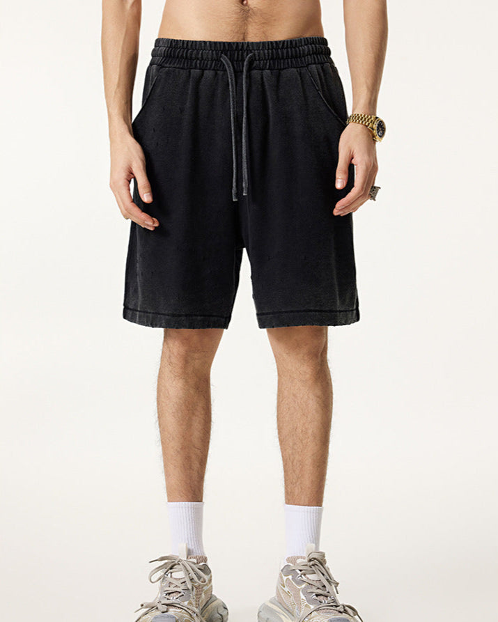 Male model wearing black washed drawstring shorts with a relaxed fit, styled with white socks and sneakers