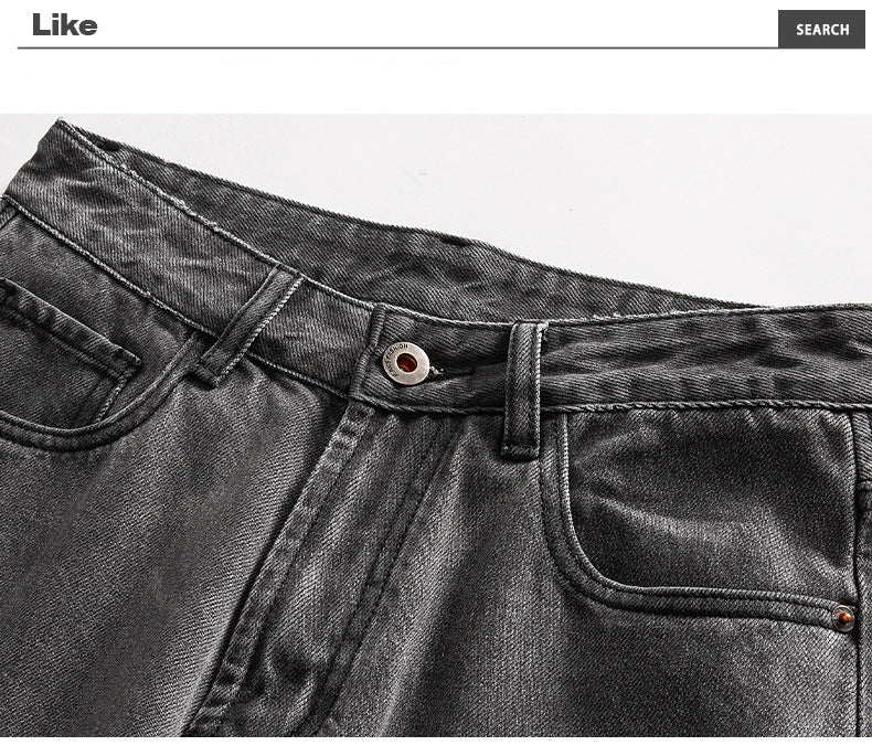 Close-up detail of washed black denim waistband with metal button and pocket construction