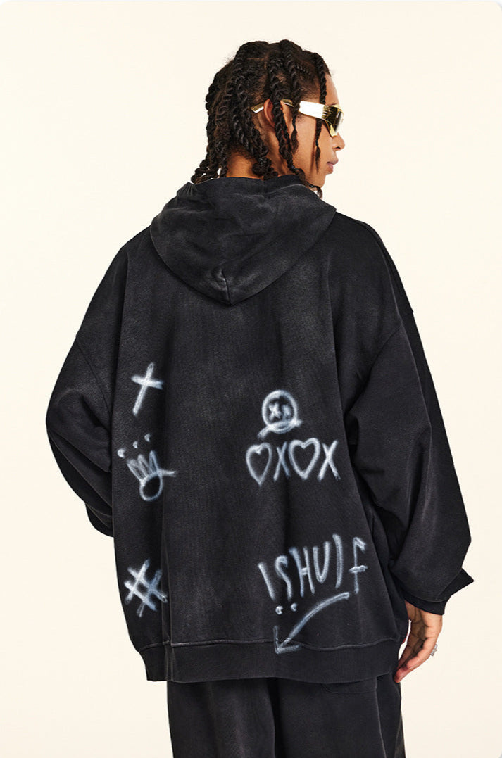 Rear view of model with twisted braids wearing black hoodie featuring graffiti designs and white painted symbols