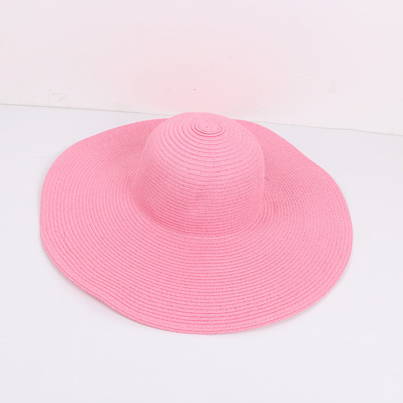 Pink wide-brimmed sun hat with a structured design, laid flat against a white background.