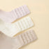 A detailed view of bra back closures in beige, white, and pink, highlighting the adjustable four-row, three-hook design.