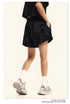 Side view of black washed shorts with elastic waistband, paired with white socks and chunky sneakers
