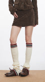 Close-up of model’s lower half highlighting brown corduroy skirt paired with cream striped socks and brown shoes.
