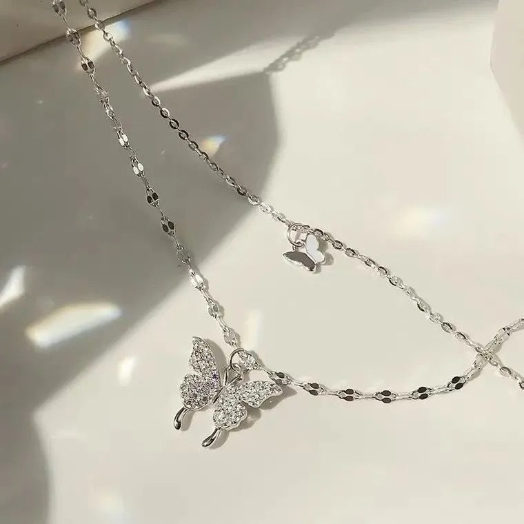 Close-up of silver double butterfly necklace with crystal details on white background