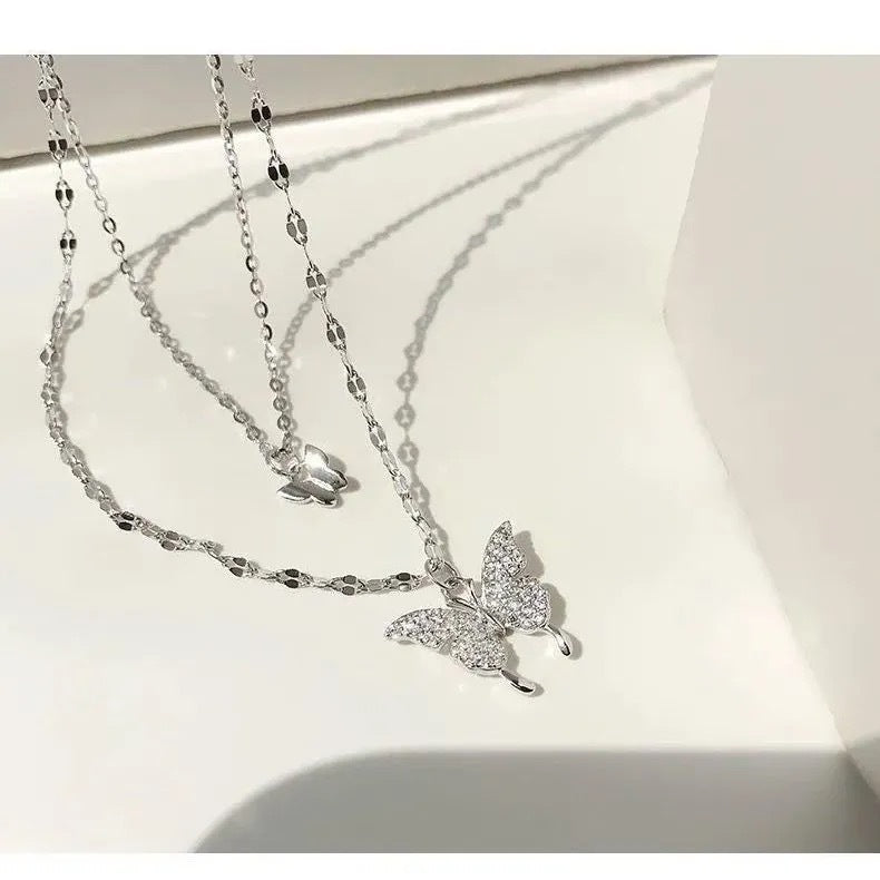 Detail shot of layered silver necklace with crystal butterfly pendant casting shadows