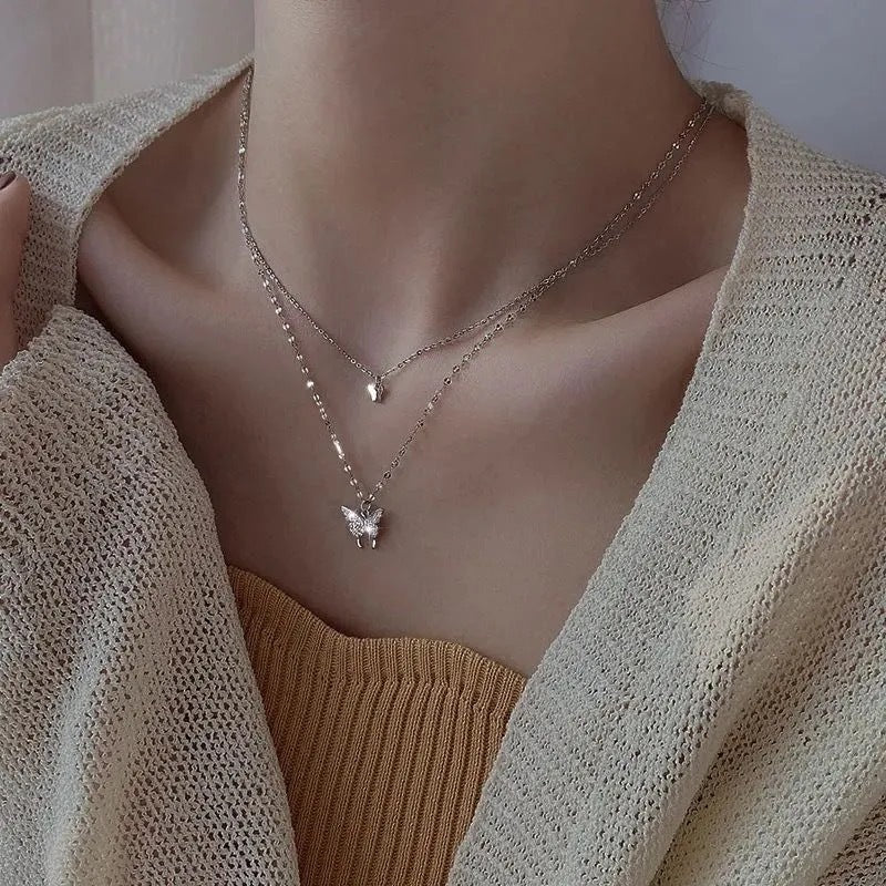 Delicate double-strand necklace with butterfly charms shown with cream knit cardigan