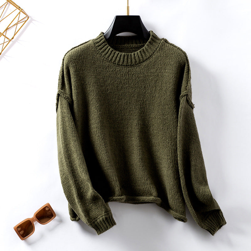 Olive green knit sweater on display hanger with tortoise sunglasses, flatlay styling