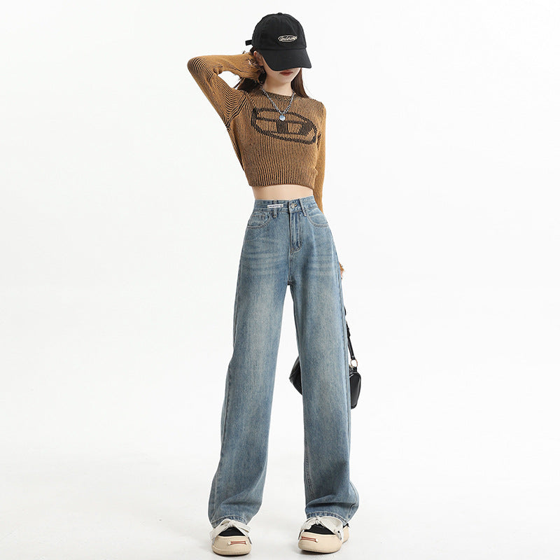 Loose-fit light blue denim jeans paired with cropped brown sweater and casual sneakers, embodying relaxed fashion