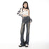 A woman in vintage-wash black denim wide-leg jeans, a monochrome abstract crop top, and chunky sneakers, posing with a tilted stance