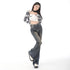 A woman in high-waisted dark-wash flared jeans and a stylish cropped top, leaning slightly to one side with one foot crossed over the other