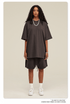 Woman with curly hair wearing dark brown oversized T-shirt and shorts set with white sneakers