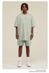 Man with dreadlocks wearing mint green oversized T-shirt and shorts set with white sneakers