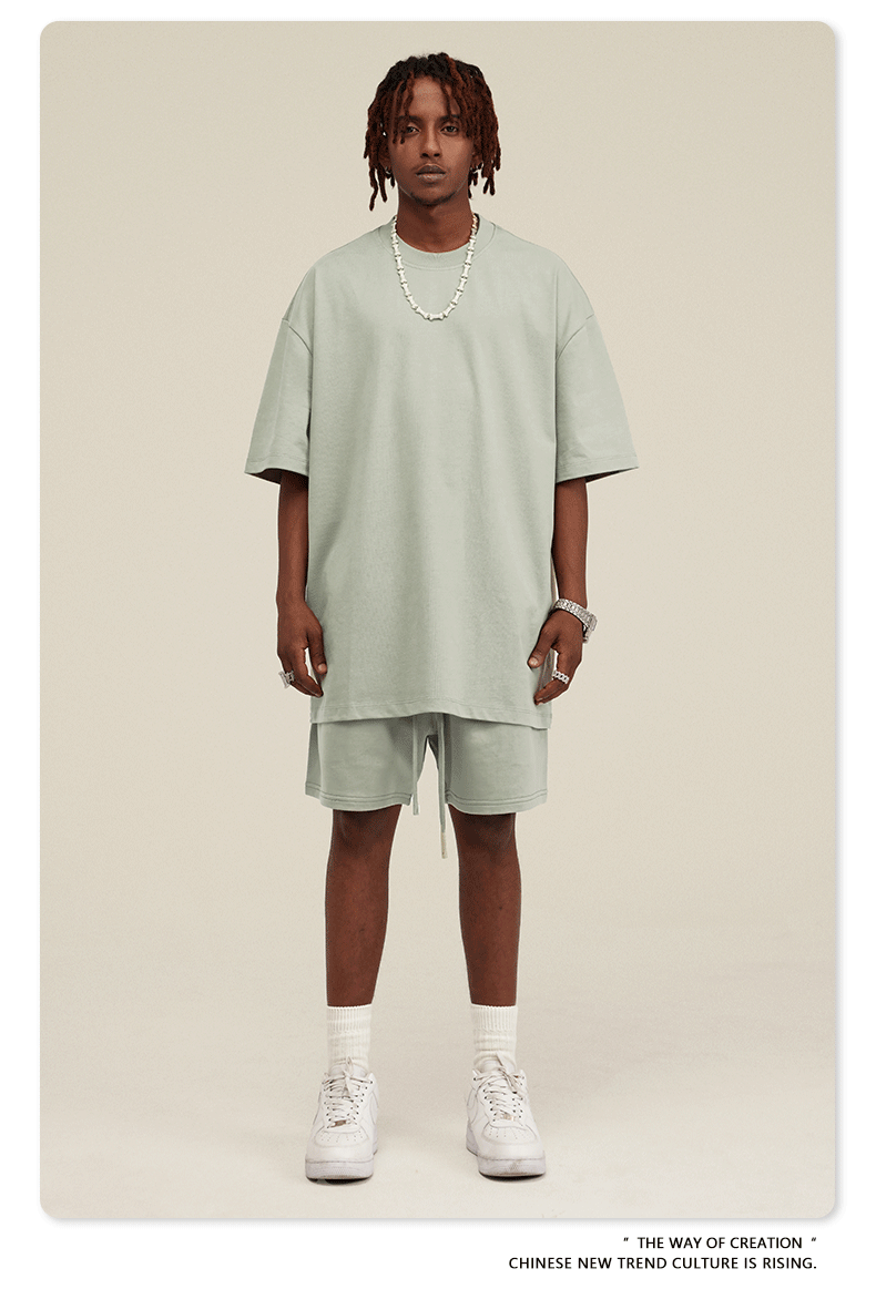 Man with dreadlocks wearing mint green oversized T-shirt and shorts set with white sneakers