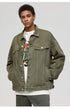 A man modeling olive denim jacket with front pockets over white graphic tee with colorful print