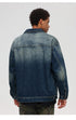 Back view of male model showing denim jacket's faded wash detail