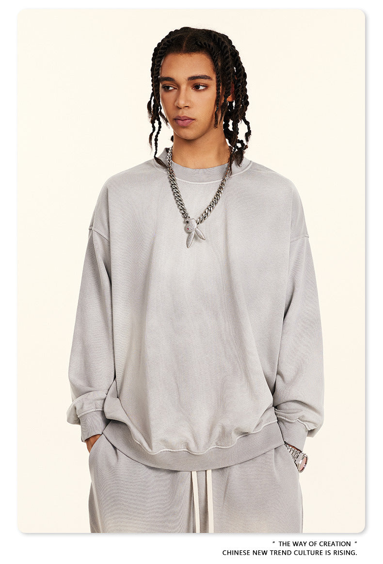 Light grey oversized sweatshirt styled with silver chain necklace and pendant, showcasing relaxed shoulder design