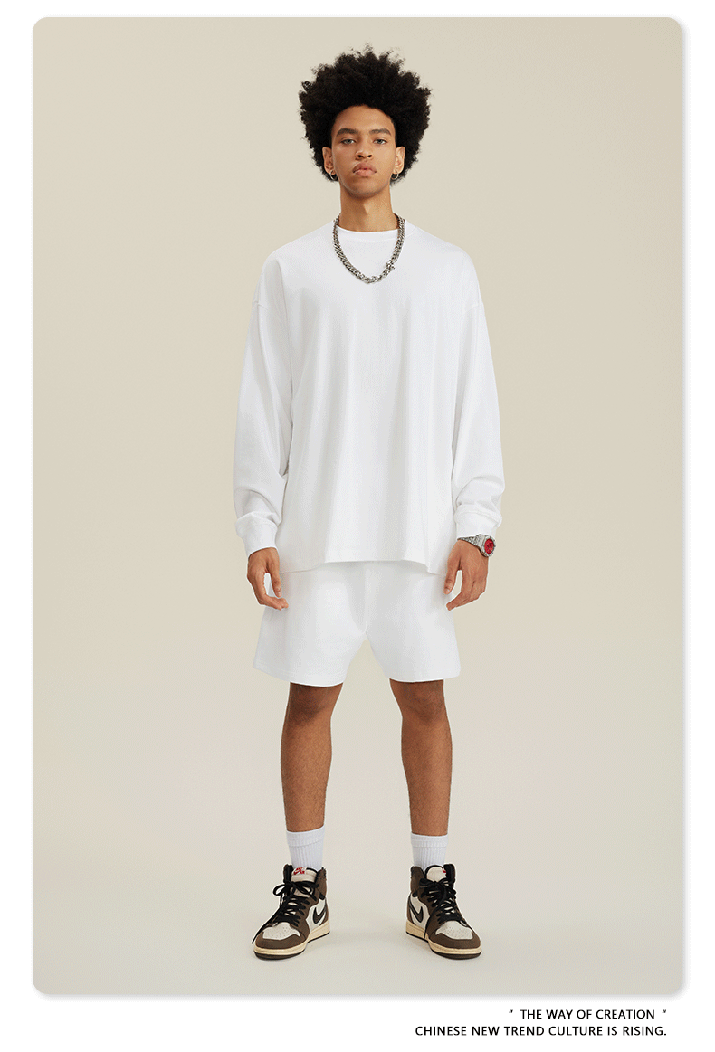 Man with afro in white sweatshirt and shorts set with chain necklace and high-top sneakers