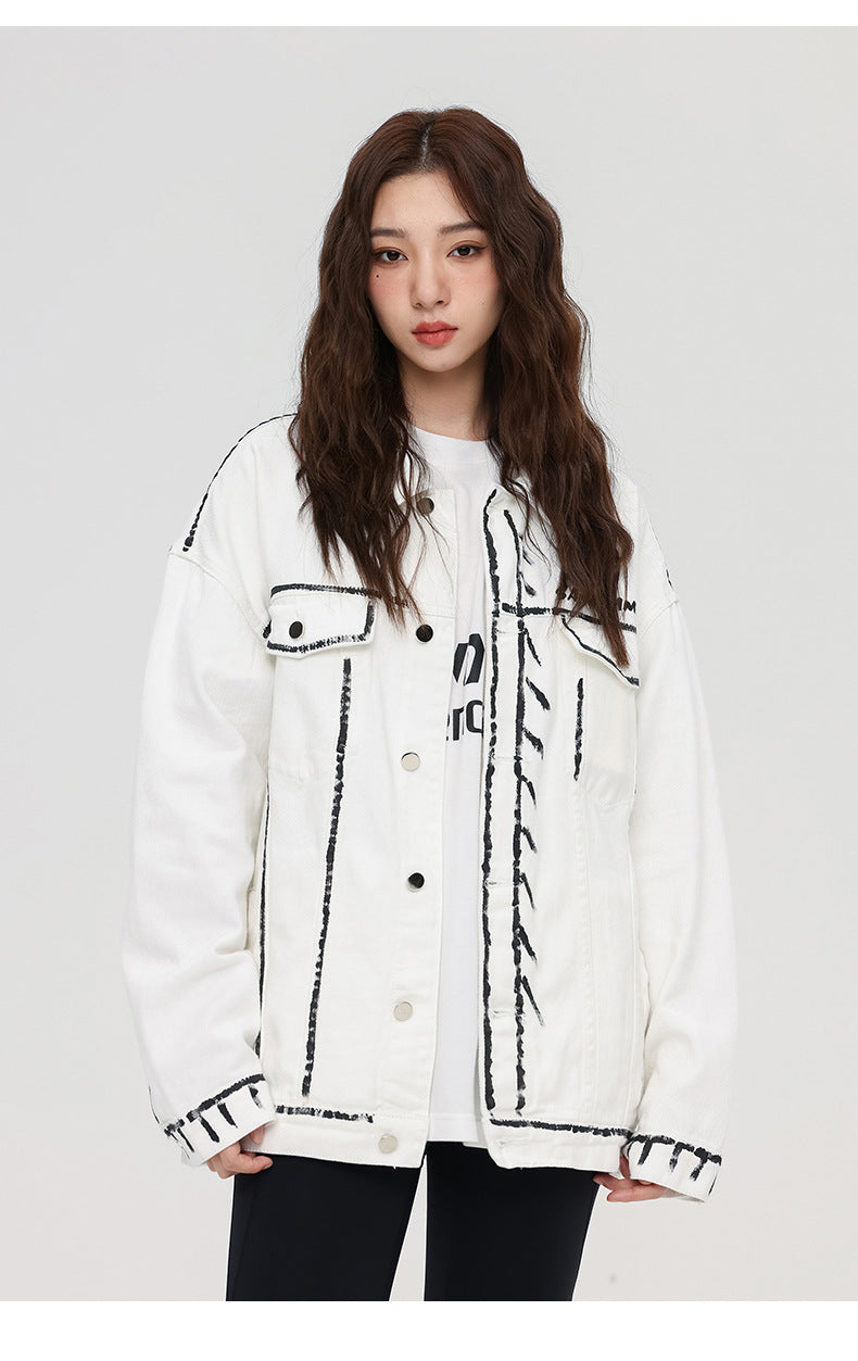 A woman is looking directly at camera. Wearing white SANHOMME outline denim jacket with black contrast stitching over white tee against gray backdrop