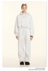 White Sweatshirt and Joggers Set with Accessories – Model wears an oversized white hoodie and joggers, accessorized with layered jewelry, sunglasses, and black shoes
