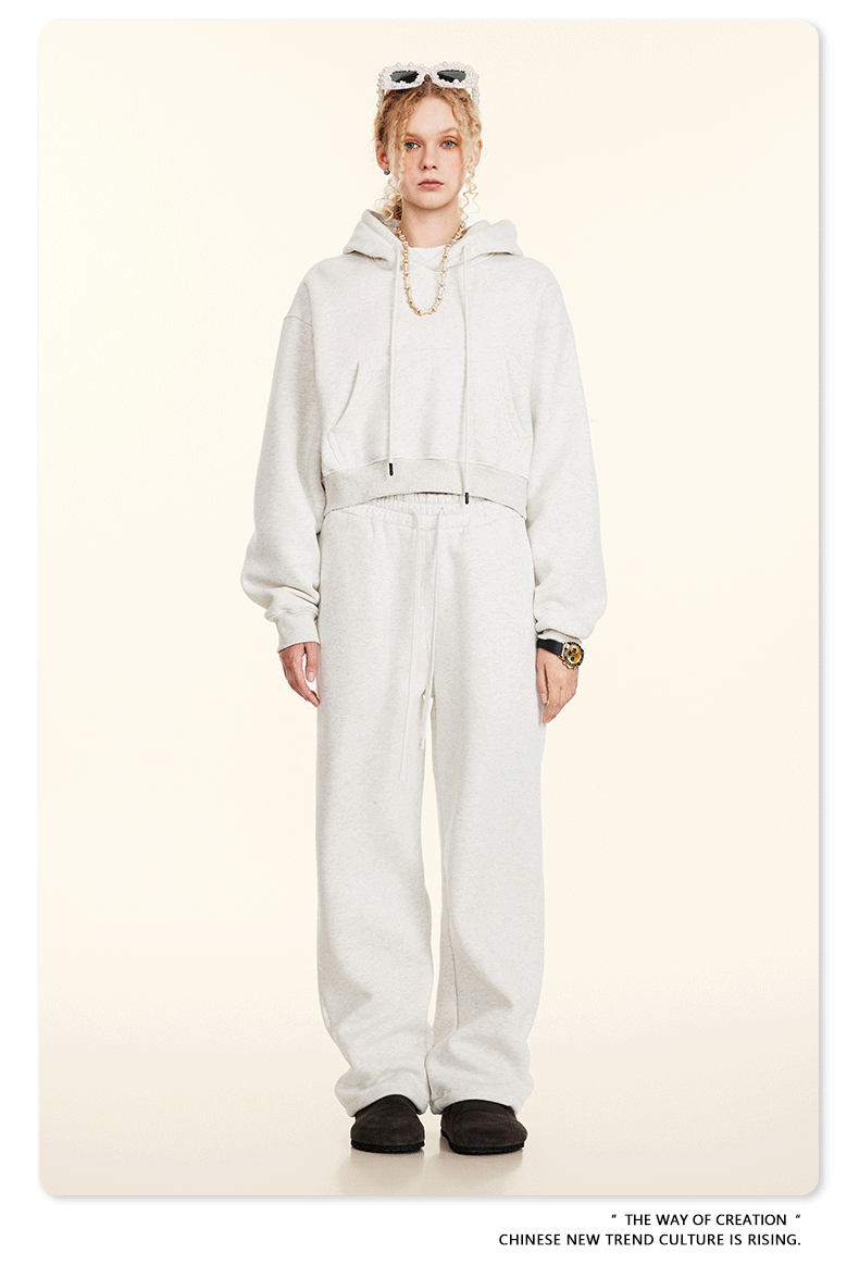 White Sweatshirt and Joggers Set with Accessories – Model wears an oversized white hoodie and joggers, accessorized with layered jewelry, sunglasses, and black shoes