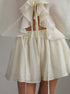 White ruffled top and shorts set on a neutral background