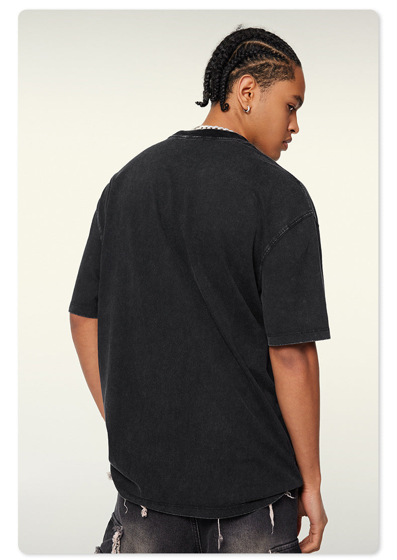 Back view of model with braided hairstyle wearing black oversized t-shirt and distressed denim against white background