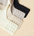 Three seamless bra closures in nude, white, and black, featuring hidden hook-and-eye clasps for an adjustable fit.