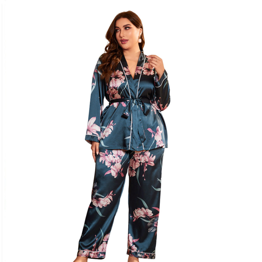 Dark blue-green satin pajama set with floral print, including a wrap-style top with tie waist and matching wide-leg pants