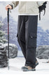 Side view of black cargo pants with hiking pole, showcasing large side pocket design and technical outdoor styling