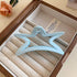 A pastel blue star-shaped acrylic hair claw, resting inside an elegant jewelry box.