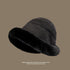 Charcoal gray bucket hat with black faux fur trim, side view highlighting fuzzy texture, foldable travel design, taupe background