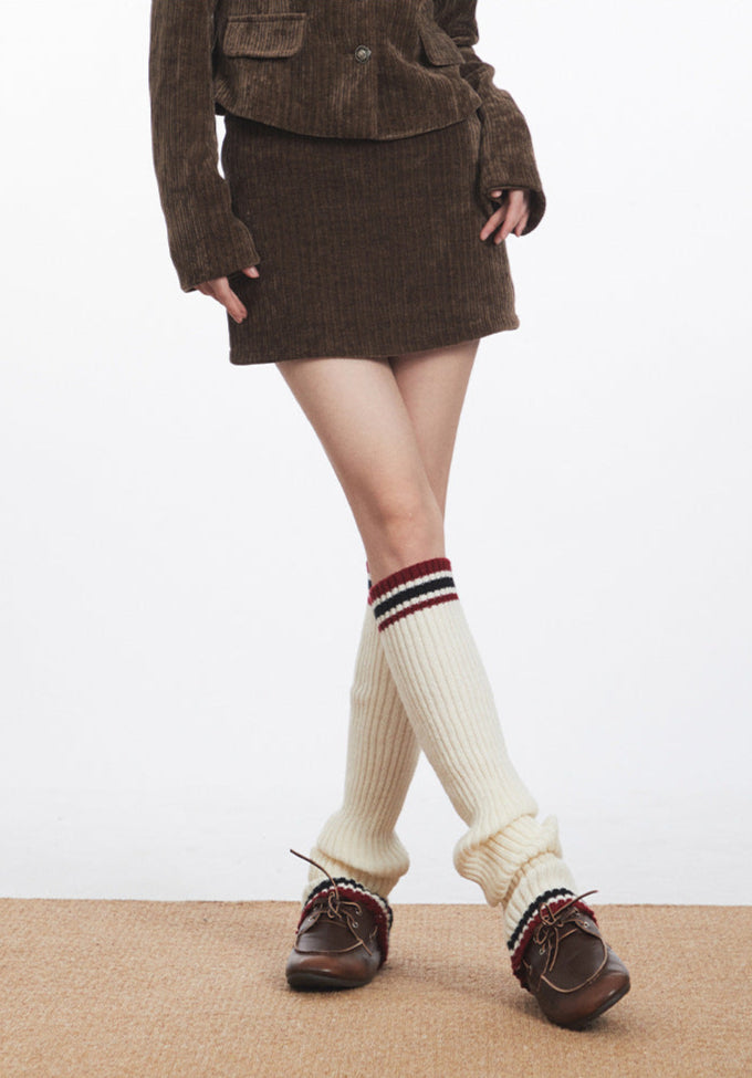 Front view of model showcasing brown corduroy skirt styled with matching blazer and retro socks.