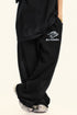 Side view of black sweatpants with Backstairs logo and distressed print effect