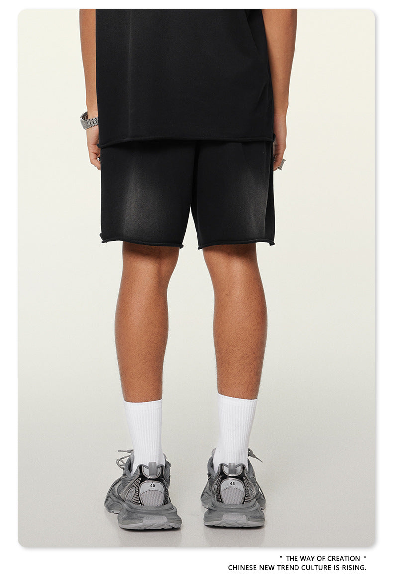 Back view of black streetwear shorts and oversized tee with metal watch accessory and chunky sneakers