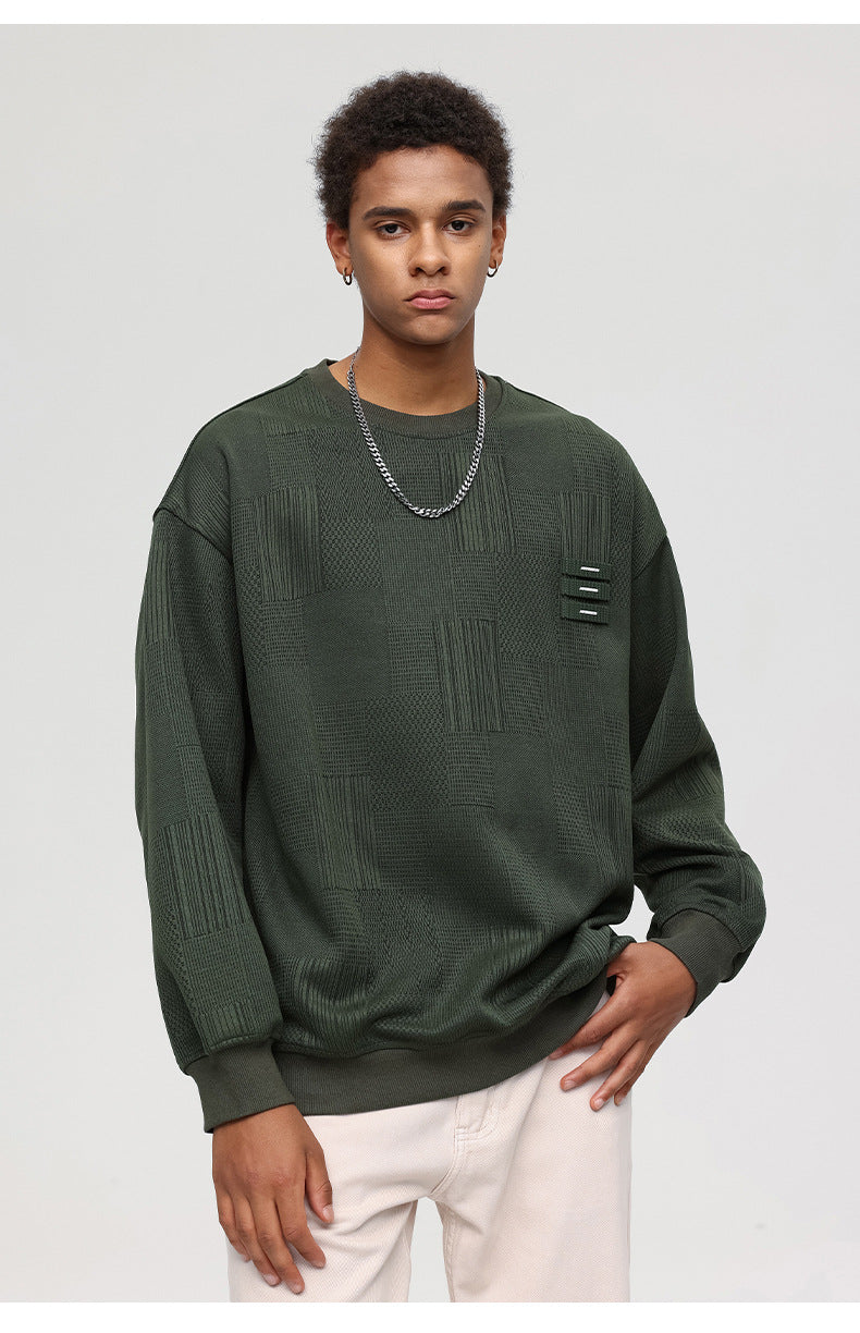 Male model in olive textured sweatshirt with decorative tabs and white pants against white background