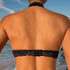 A woman's back view showing a black lace bralette with hook closure against sun-tanned skin