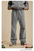 Person with hands in pockets wearing light grey zip-up hoodie and sweatpants on beige background