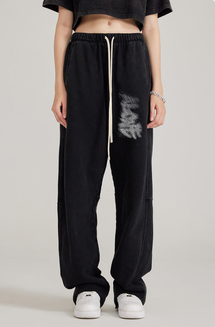 Front view of model in black crop top and black sweatpants with white drawstring and graffiti-style graphic print
