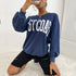 Side view of navy East Coast sweatshirt with white varsity lettering and gold accessories