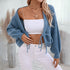 Cropped blue knit cardigan with white tie front, paired with white crop top and jeans, accessorized with layered gold necklaces