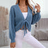 Close-up of blue ribbed cardigan with tie front detail and V-neckline, worn with white pants