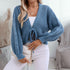 Blue knit cardigan with balloon sleeves and front tie closure, paired with white denim and chain strap bag