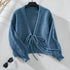 Blue chunky knit cardigan with tie front closure on hanger against white background