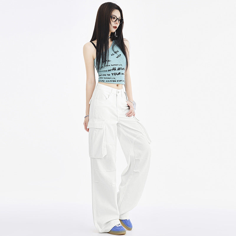 A side view of a woman in a blue crop top and white wide-leg cargo pants, styled with glasses and blue sneakers, in a bright setting