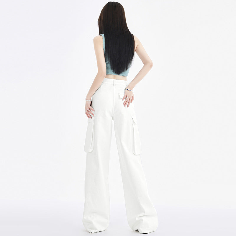 A woman stands with her back to the camera, showcasing white cargo pants with multiple pockets, against a clean white backdrop