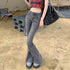 Woman wearing gray flared jeans with frayed hem and plaid crop top at campsite, styled with casual slip-on shoes