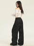 A model is posing from behind in an off-shoulder white textured top, ultra-wide black denim jeans, showing contrast stitching and platform shoes